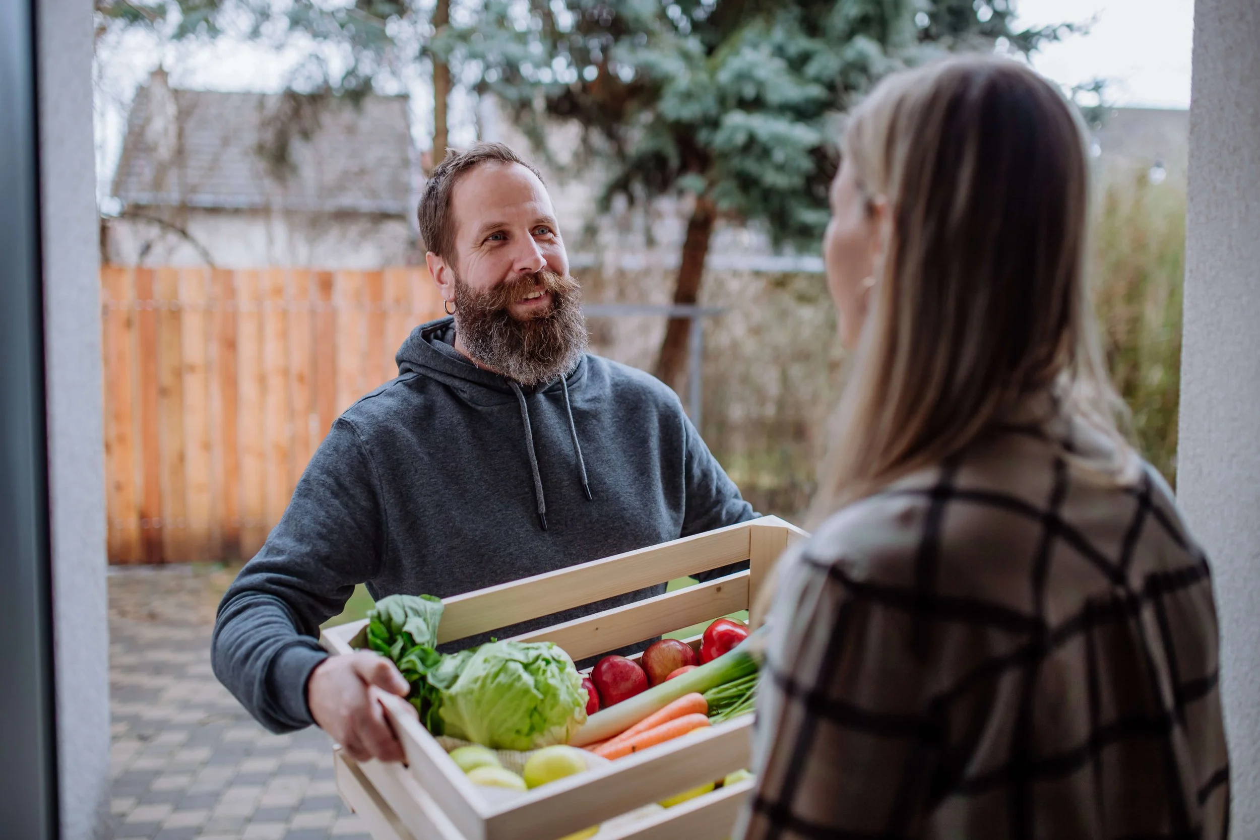 Smiling man delivering a box of fresh vegetables and fruit